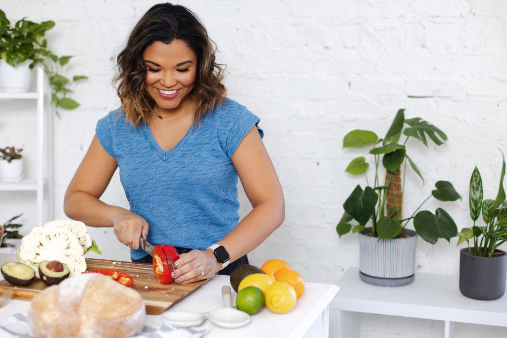 Woman chopping a red bell pepper in a kitchen setting