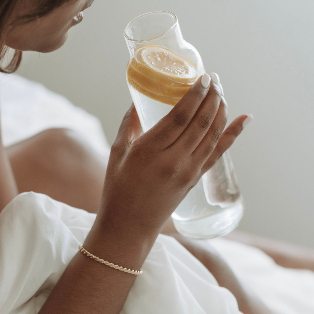 Picture of woman's arm and hand holding water bottle with lemon slices in it.