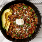Bowl of veggie-packed turkey chili topped with avocado, sour cream and cilantro