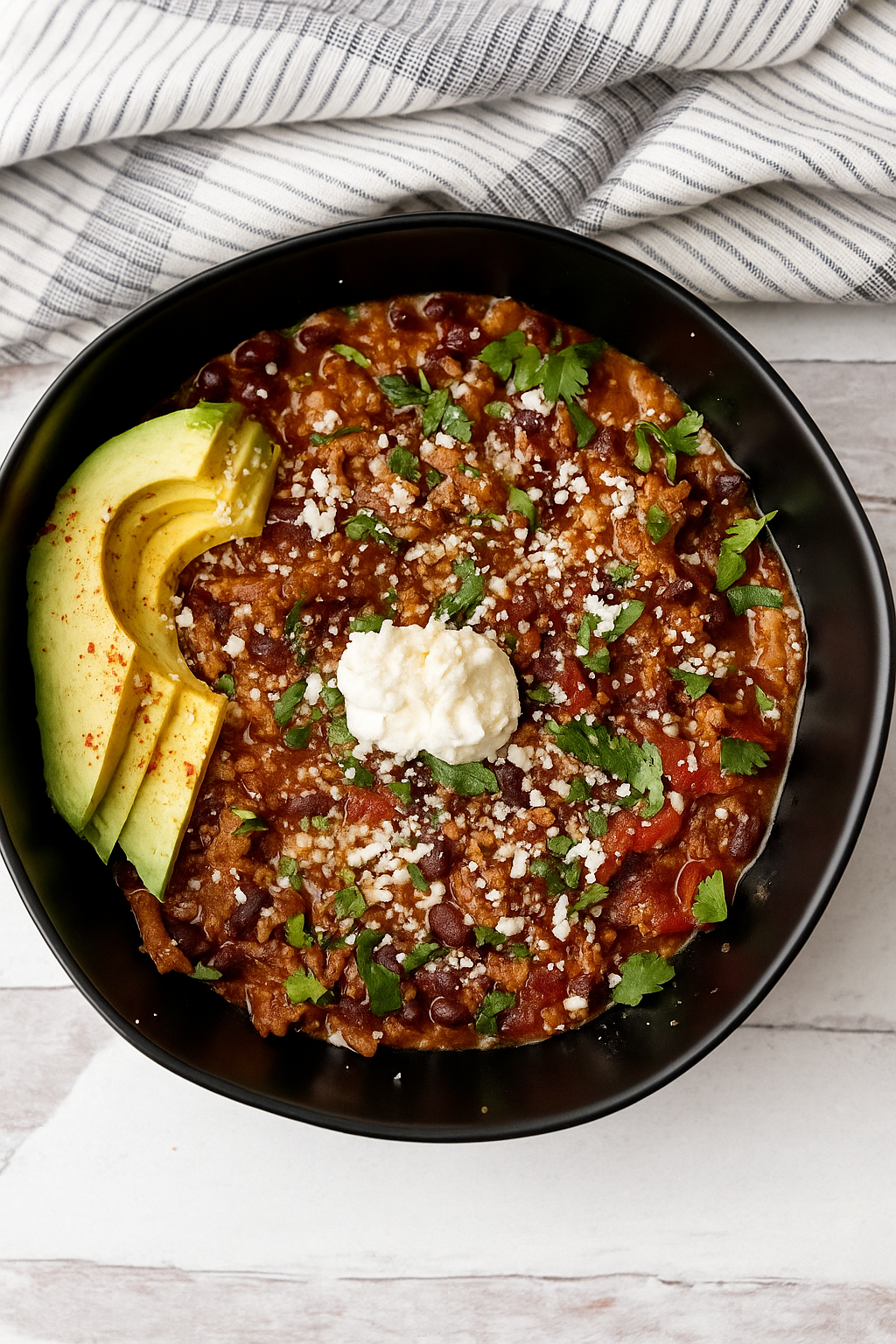 Bowl of veggie-packed turkey chili topped with avocado, sour cream and cilantro