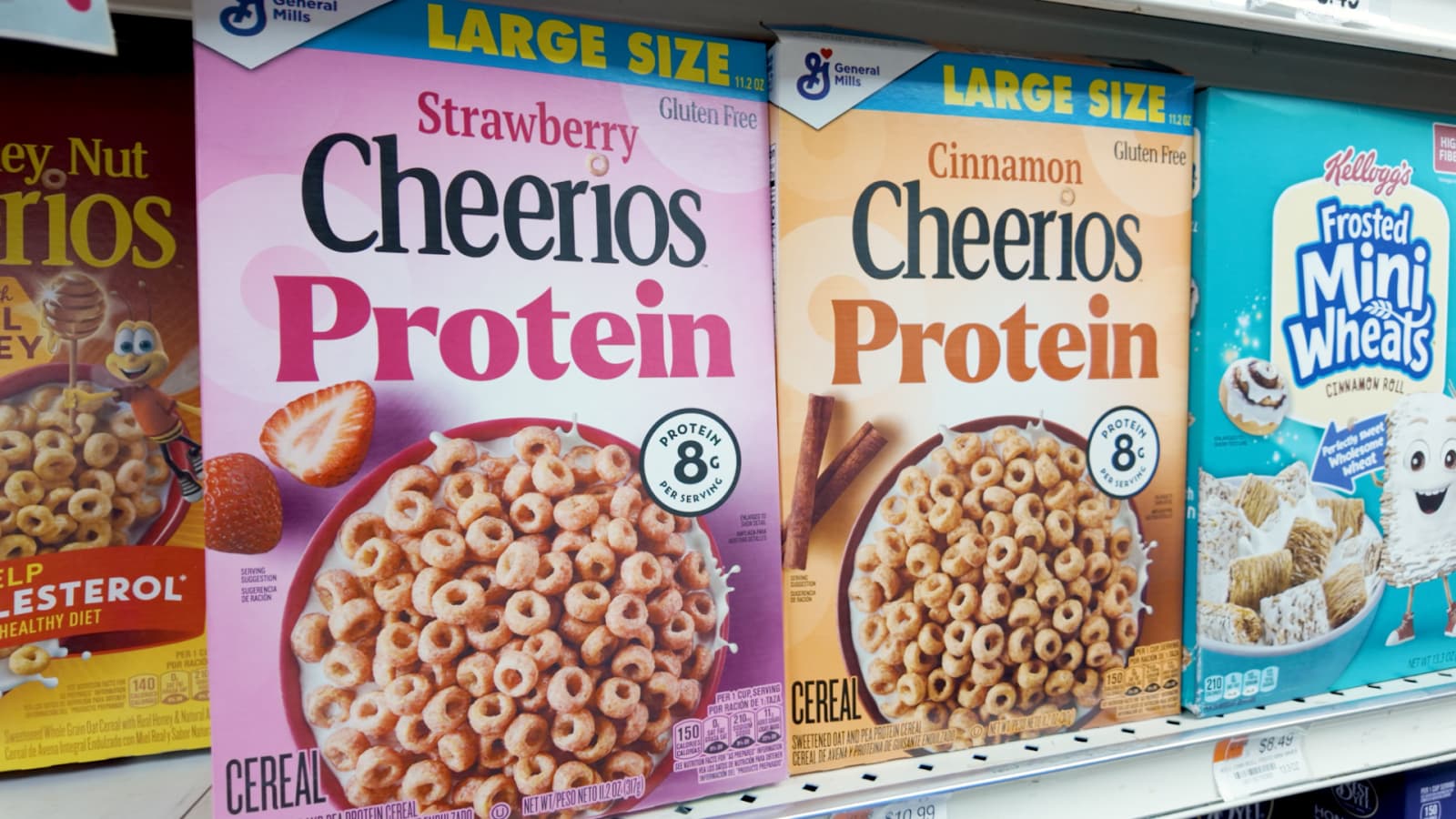 Close-up of grocery store cereal shelf featuring high-protein cereals, including multiple boxes labeled “protein,” highlighting the trend of protein-enriched foods.
